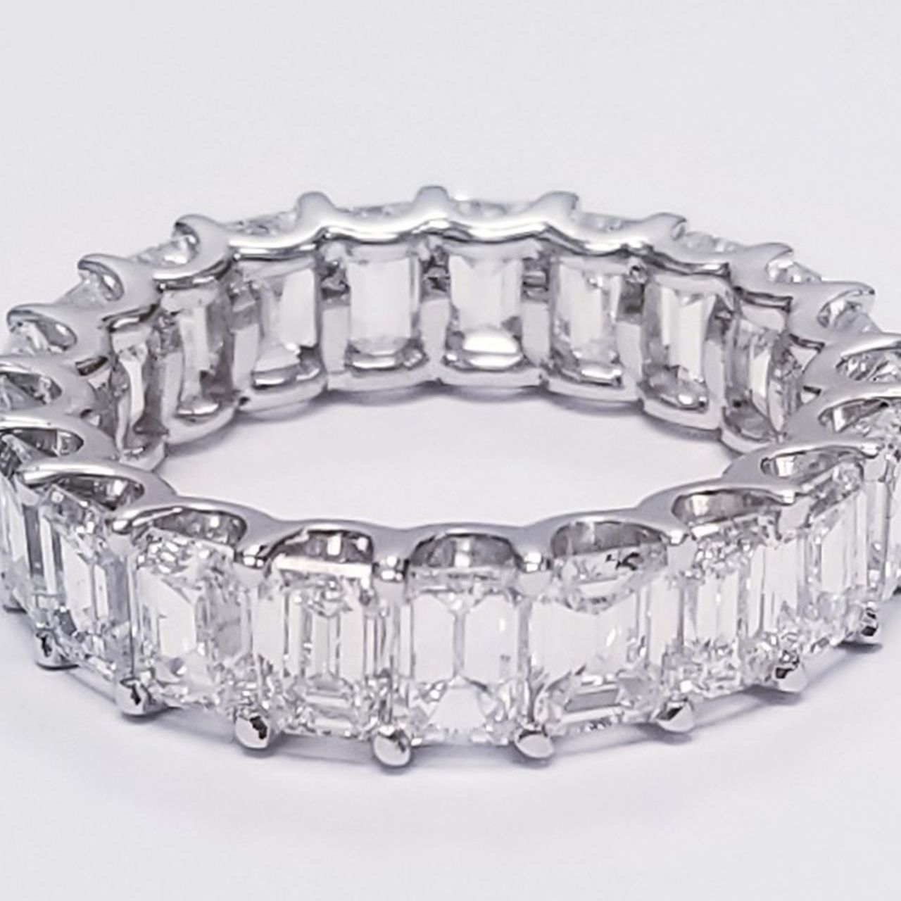 Eternity band in platinum with  shared U-prong set emerald cut diamonds.  D6.79ct.t.w.