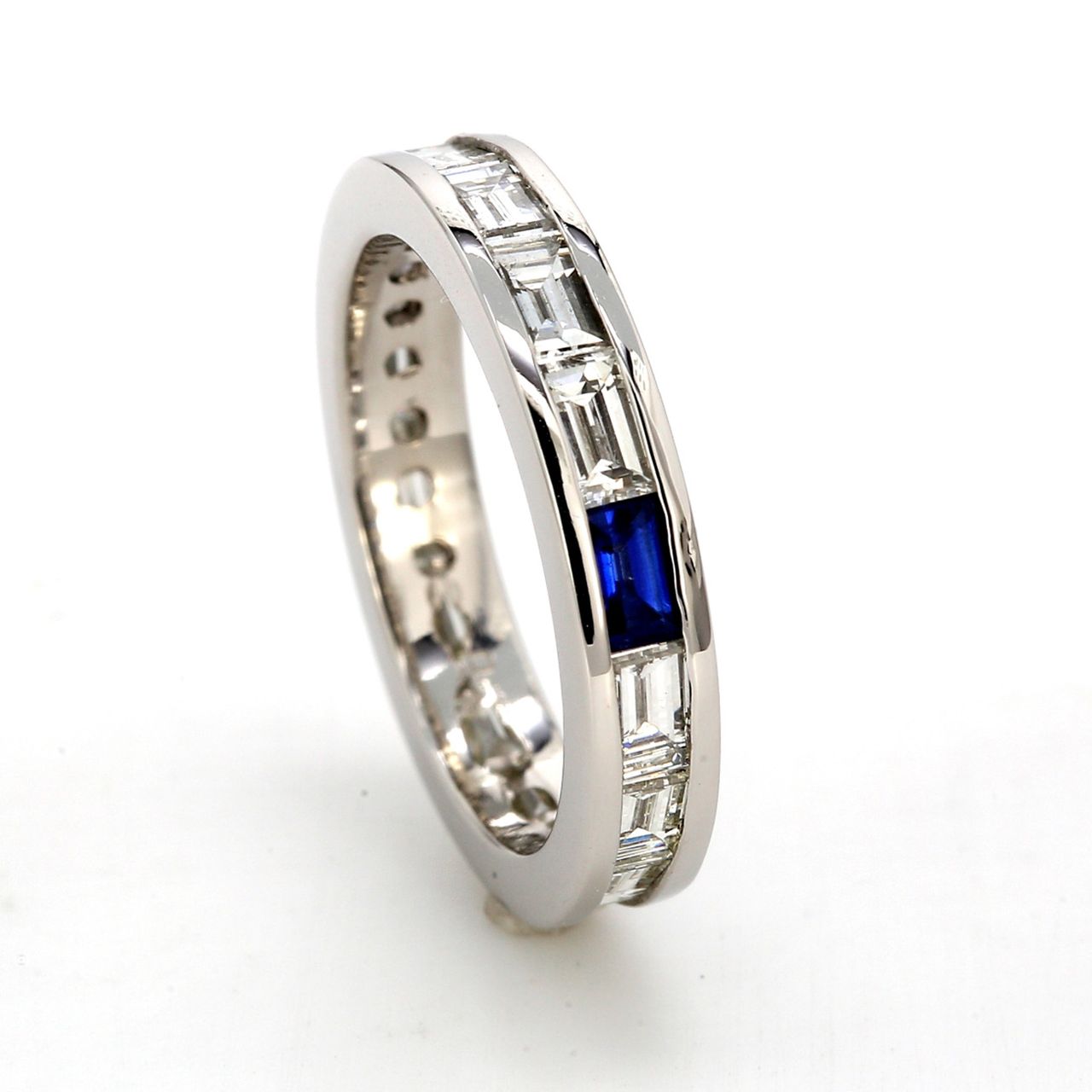 Eternity band in platinum with channel set baguette diamonds &  a baguette shaped sapphire.  D1.38ct.t.w.  Sapphire 0.12ct.