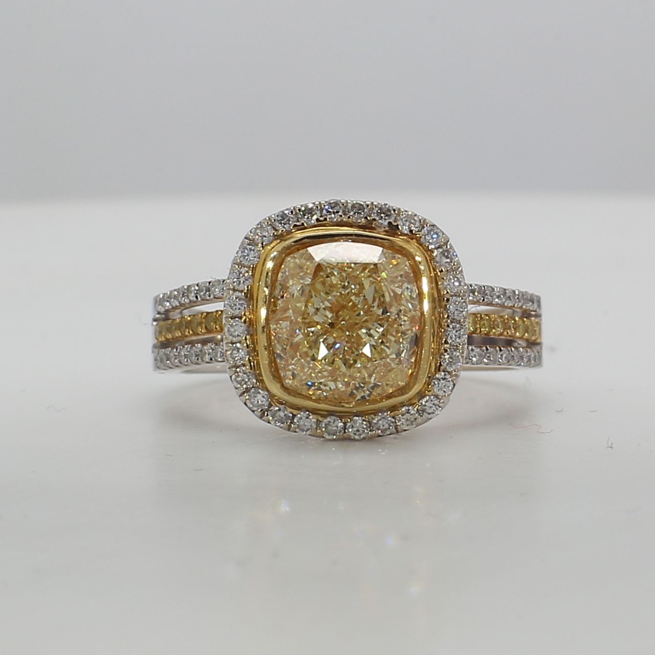 Triple shank halo ring in 18K WG with bezel set FLY/VS1 GIA certified cushion center stone and prong set white and yellow diamonds.  D3.41ct.t.w.  (Center - 3.01ct.)