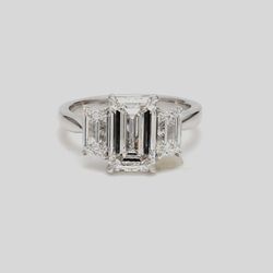 3-stone semi-mount in platinum with GIA certified E/VS2 emerald cut diamond sides.  D1.40ct.t.w.