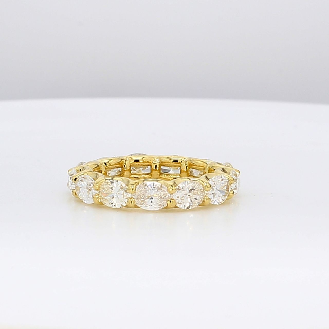 East to west style eternity band in 18K YG with 4-prong set (13) oval cut diamonds.  D3.43ct.t.w.  Size 5