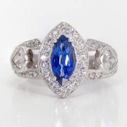 Halo ring in platinum with with bezel set pear shape sides, pave set round diamonds around 4-prong set marquise shaped sapphire center stone.  D1.20ct.t.w.  Sapphire 1.04ct.