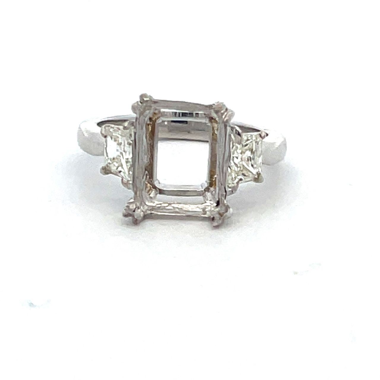3-stone semi mount in platinum with prong set trapezoid diamond side stones.  D0.84ct.t.w.  Size 6.75